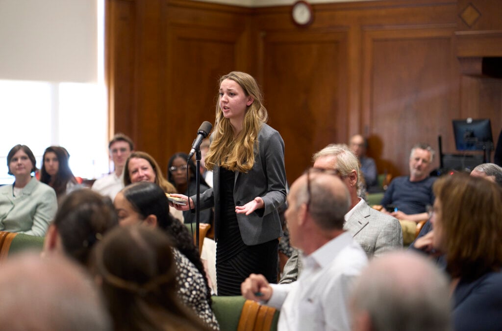 A woman in an audience standing asking a question.